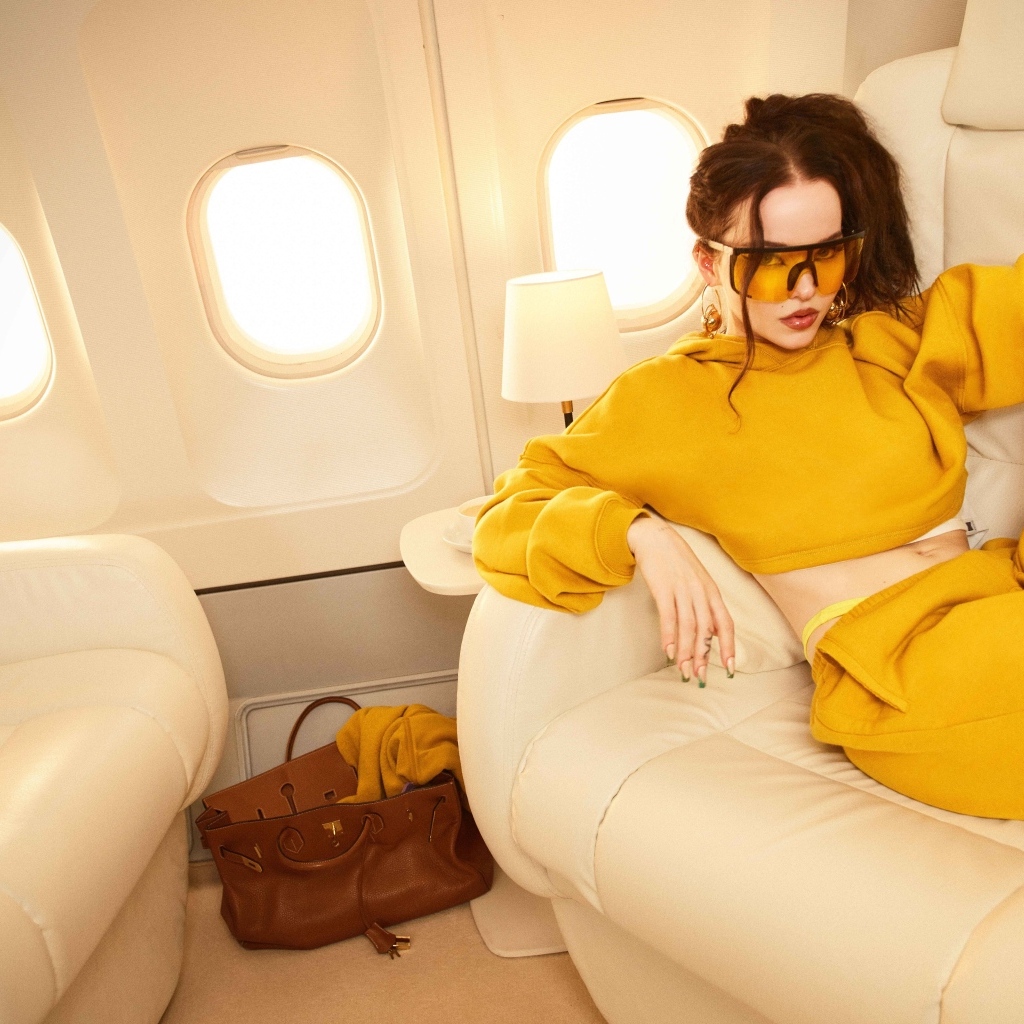 Актриса Дав Кэмерон в желтом костюме в самолете