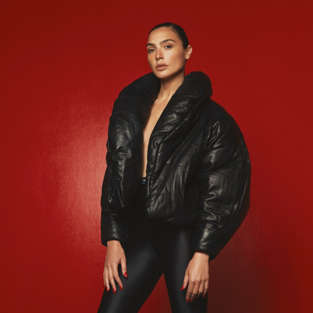 Актриса Галь Гадот в черной куртке на красном фоне