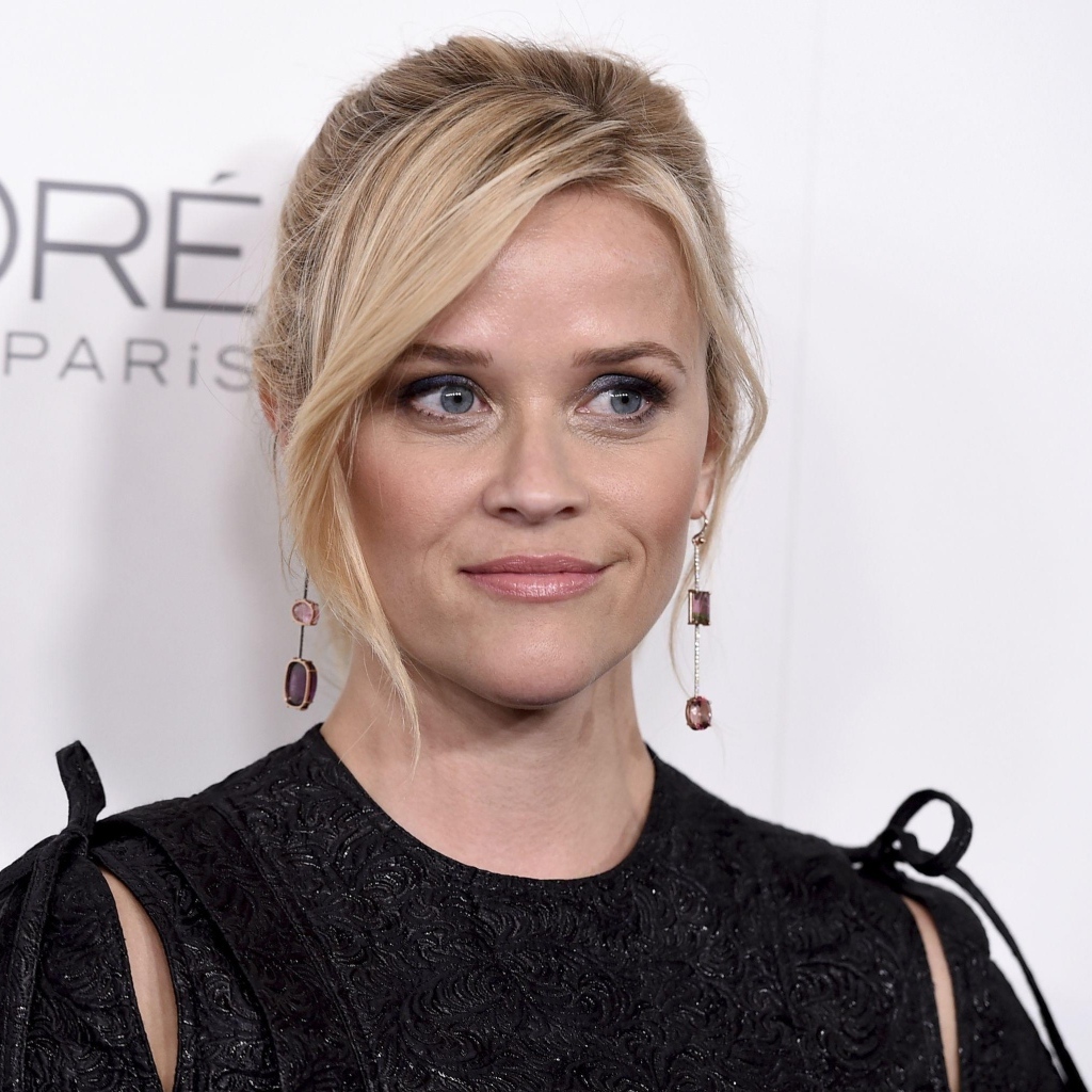 Actress Reese Witherspoon in a black dress against a wall