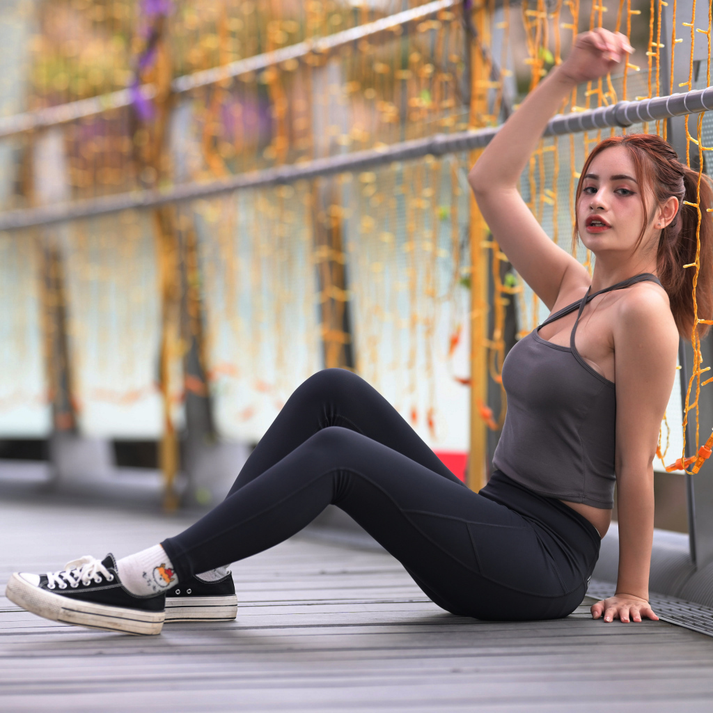 Спортивная девушка в костюме сидит на полу