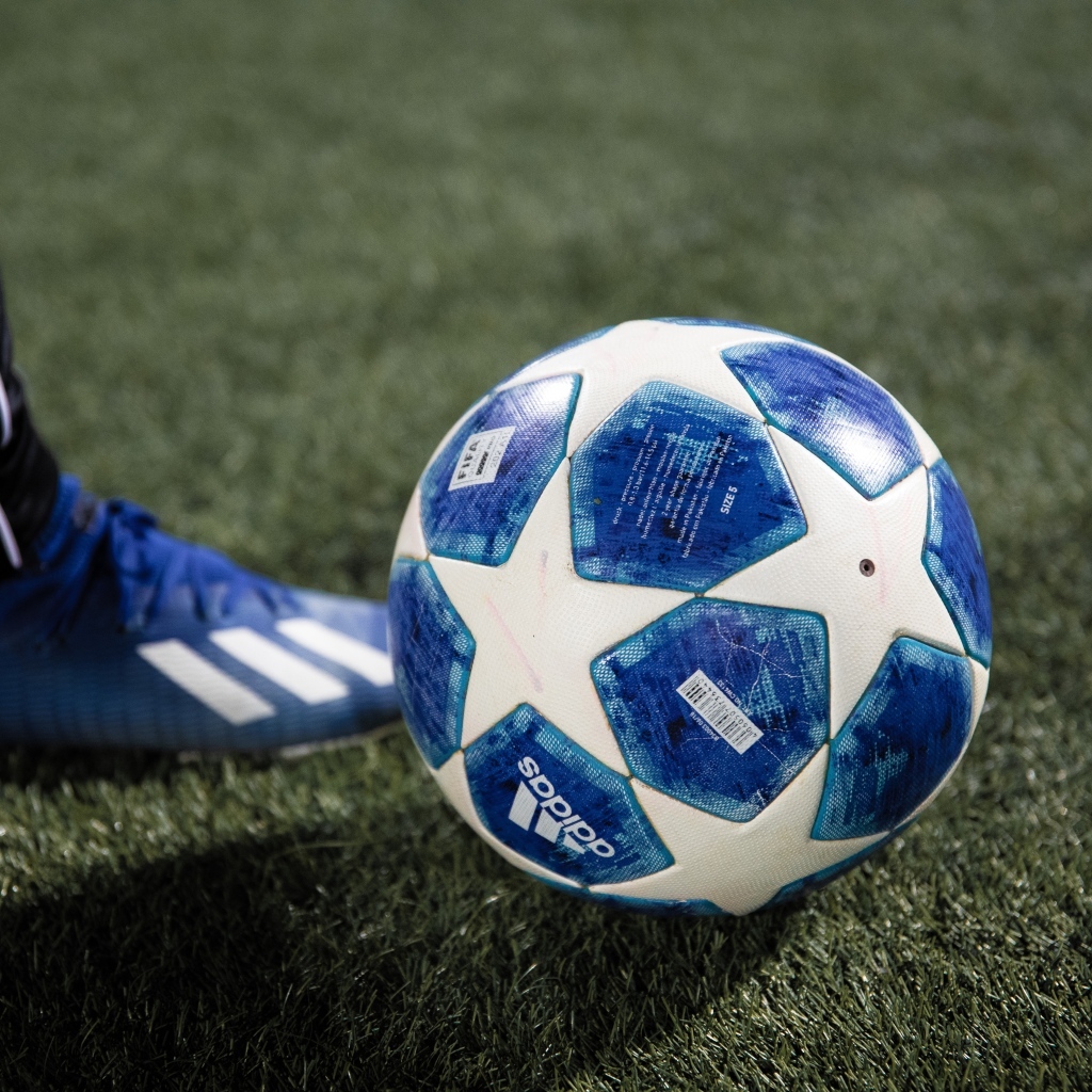 Синий футбольный мяч на зеленой траве поля