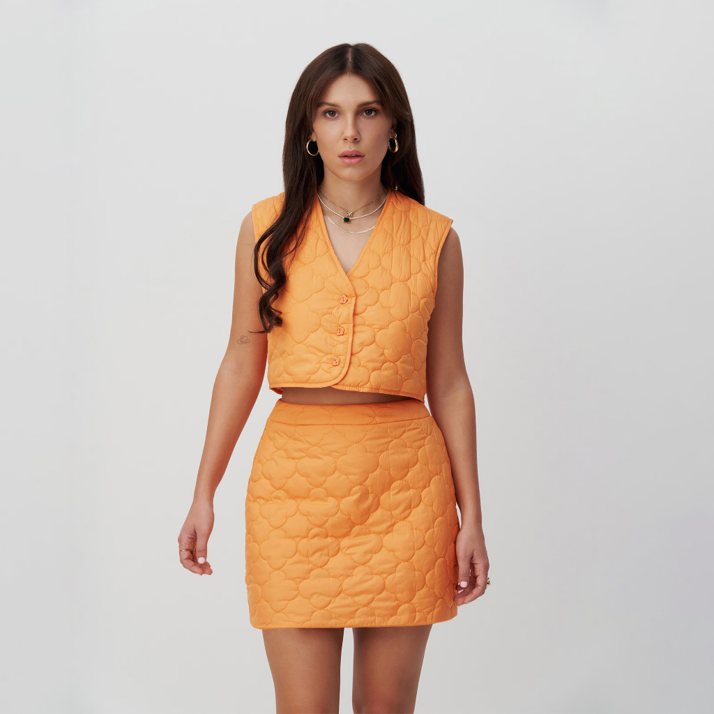 Девушка актриса Милли Бобби Браун в костюме на сером фоне