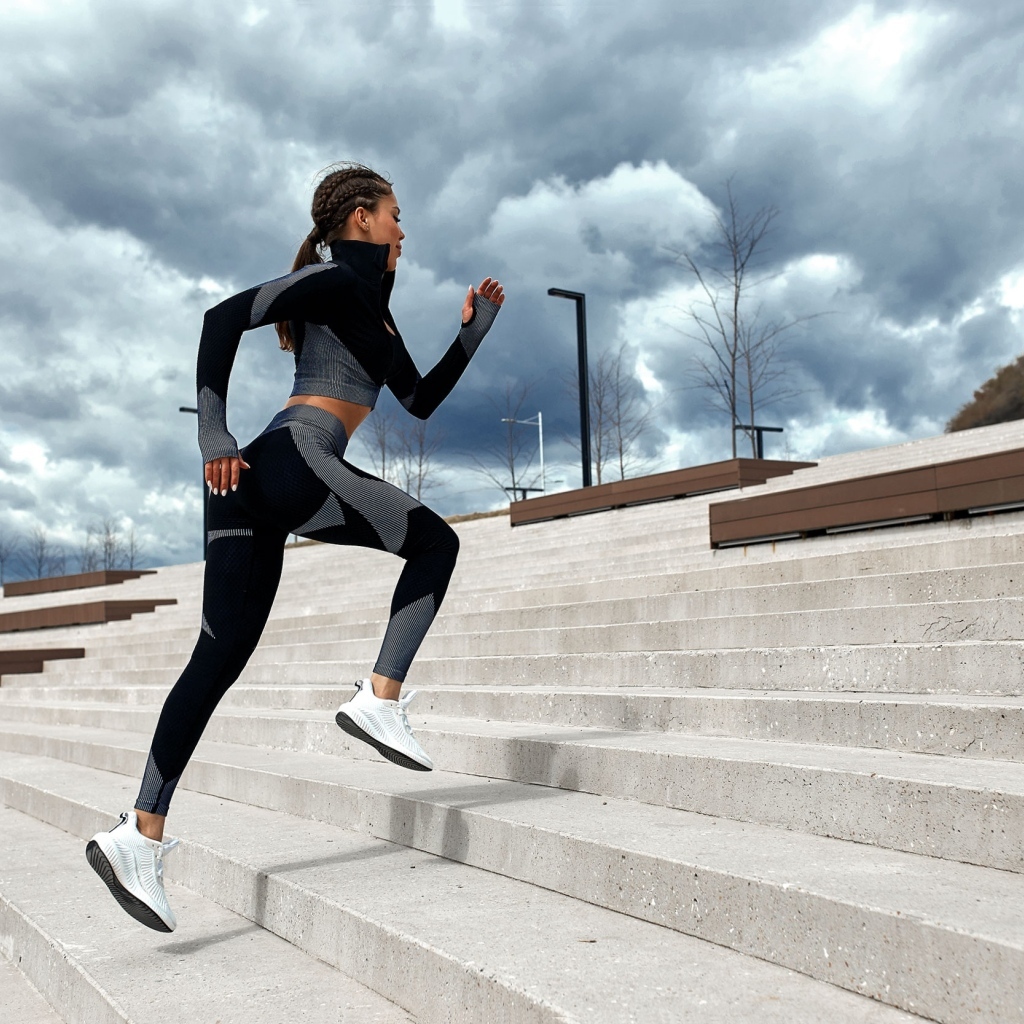 Девушка спортсменка бежит по лестнице