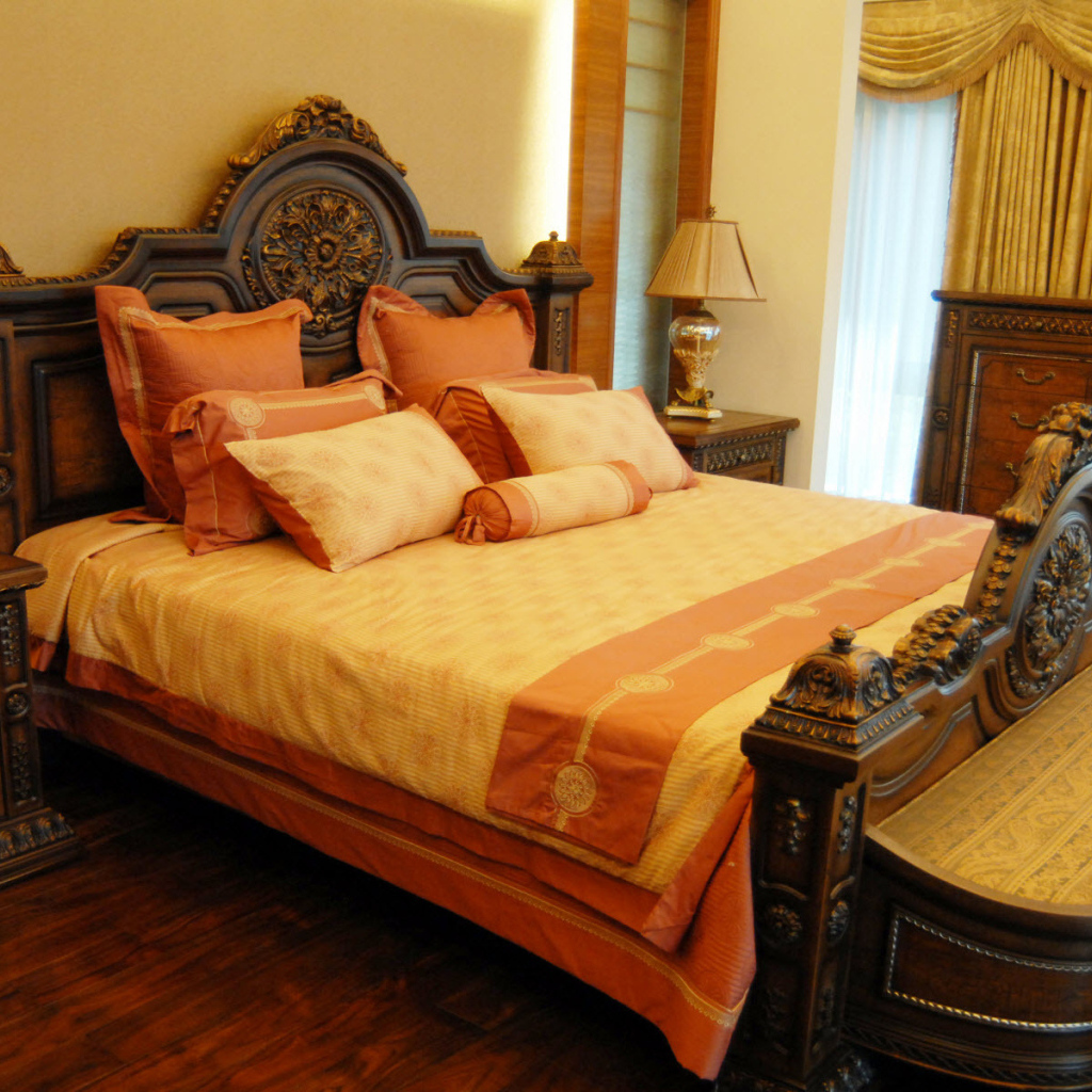 Большая деревянная кровать в спальне с оранжевым интерьером