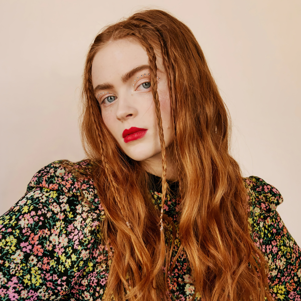 Рыжеволосая Сэди Синк на розовом фоне