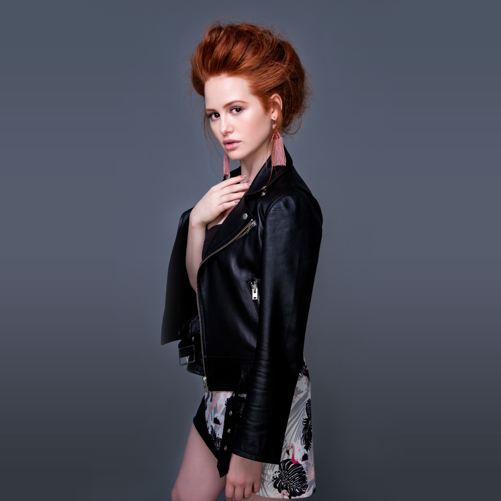 Рыжеволосая актриса Мэделин Петш в черной куртке на сером фоне