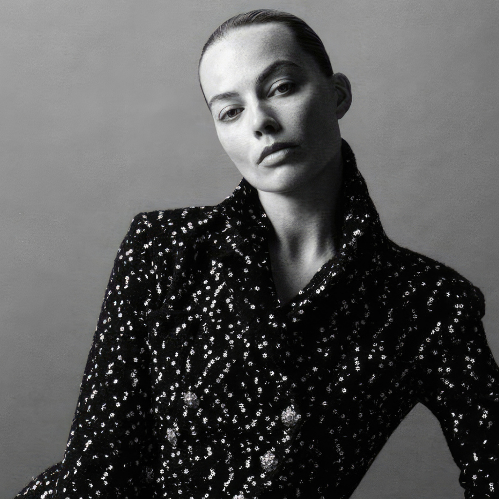 Грустная Марго Робби в блестящем пиджаке на сером фоне