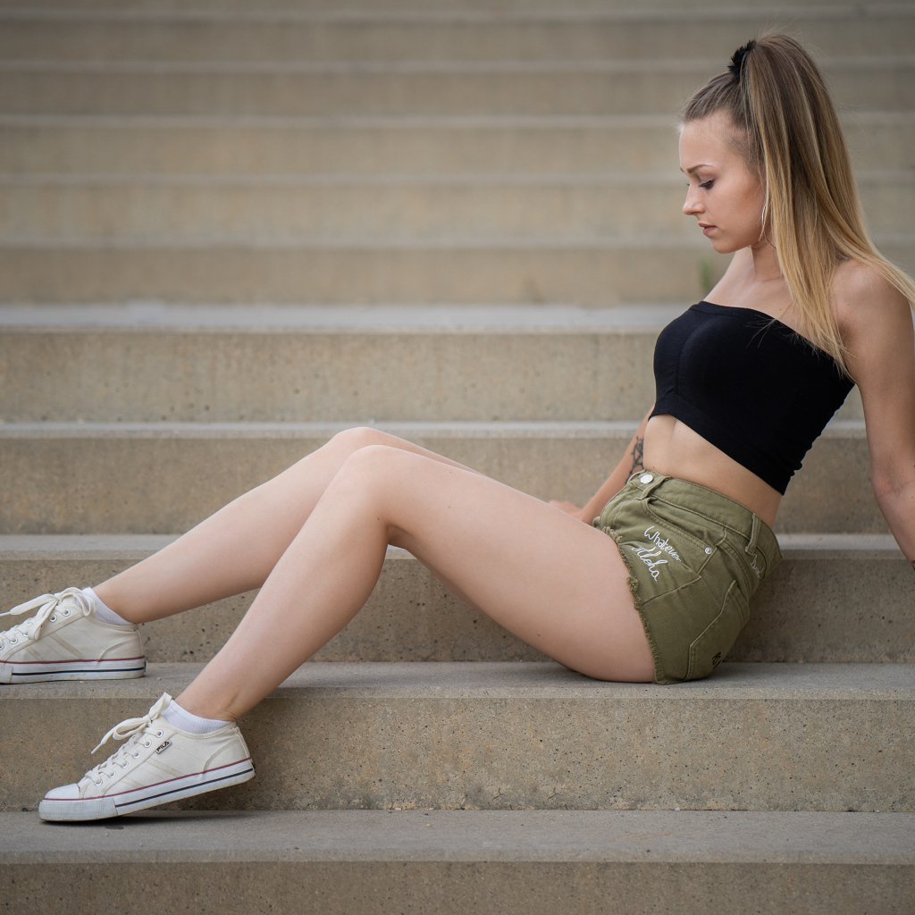 Стройная спортивная девушка сидит на ступеньках