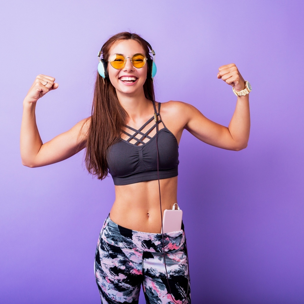 Улыбающаяся спортивная девушка слушает музыку