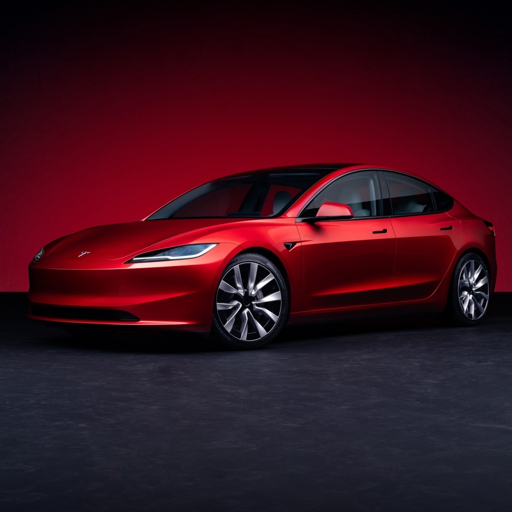Автомобиль Tesla Model 3 2023 года на красном фоне