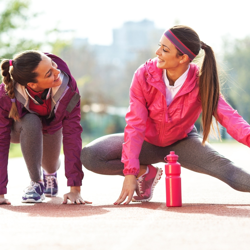 Две спортивные девушки делают растяжку 