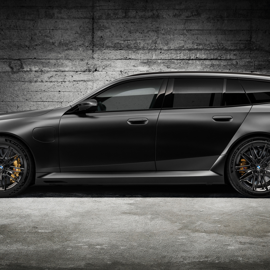 Вид сбоку на черный автомобиль BMW M5 Touring 2024 года
