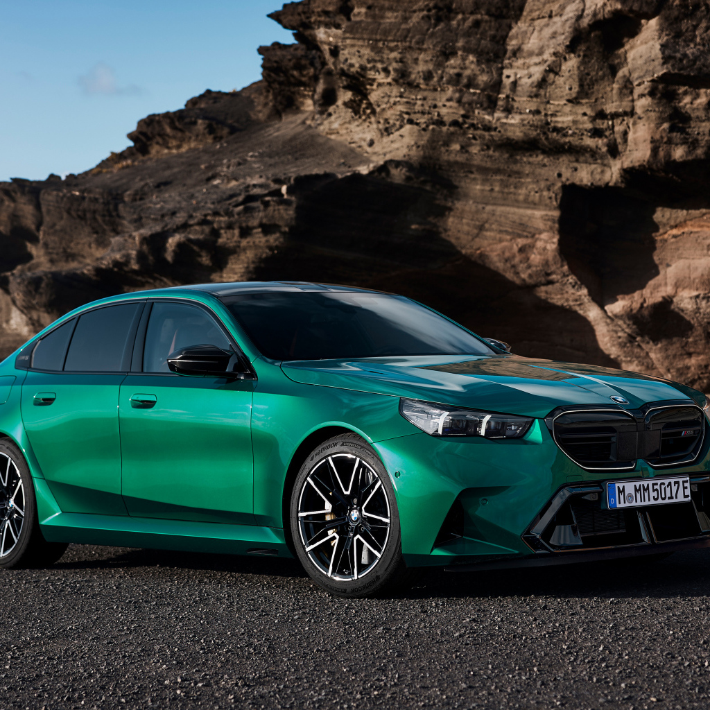 Зеленый автомобиль BMW M5 2024 года на фоне гор