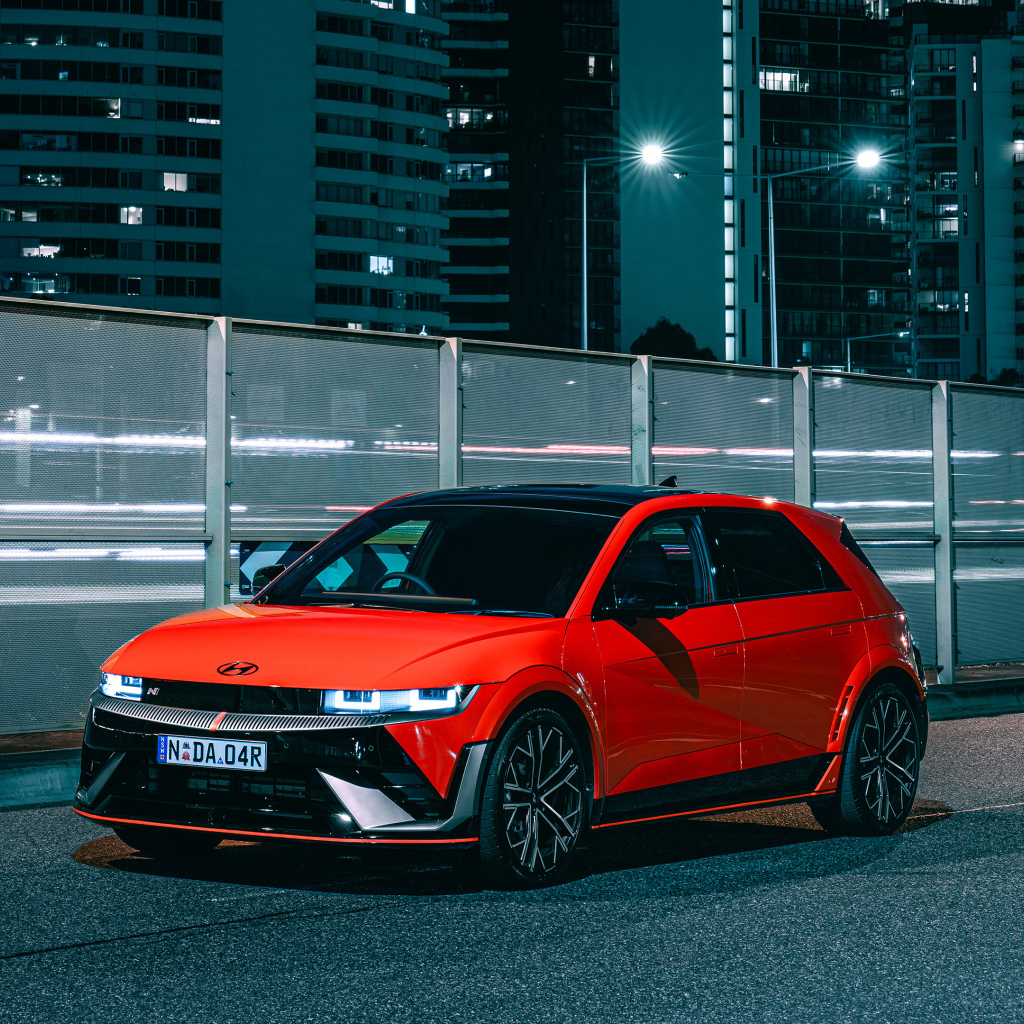 Красный автомобиль Hyundai IONIQ 5 N 2024 года у забора