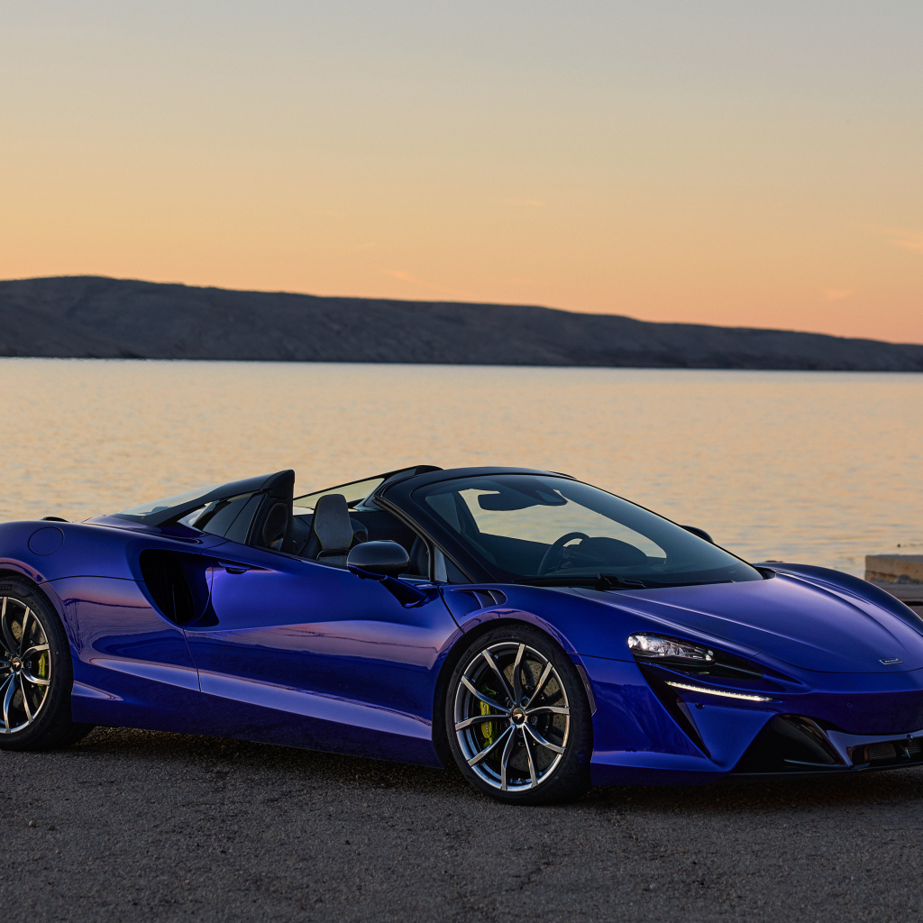 Синий быстрый автомобиль McLaren Artura Spider у воды