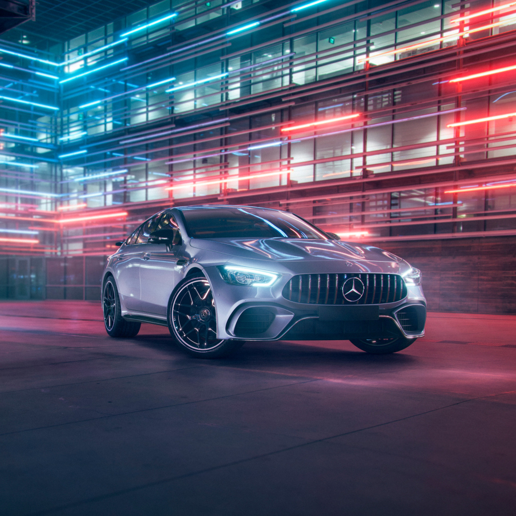 Серебристый автомобиль Mercedes AMG GT4 на фоне здания