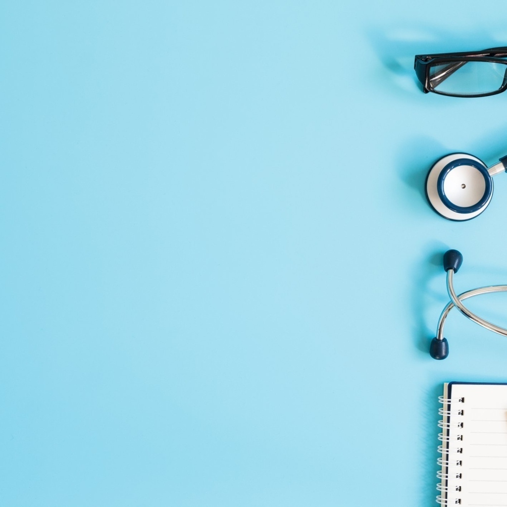 Стетоскоп, очки и блокнот на голубом фоне