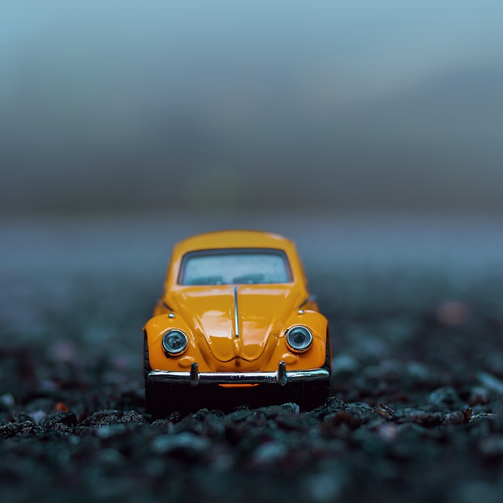 Маленькая игрушечная машинка стоит на асфальте