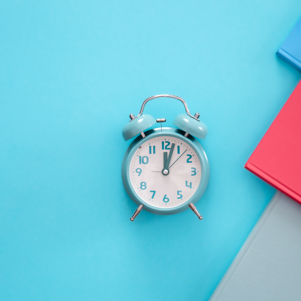 Будильник с книгами на голубом фоне