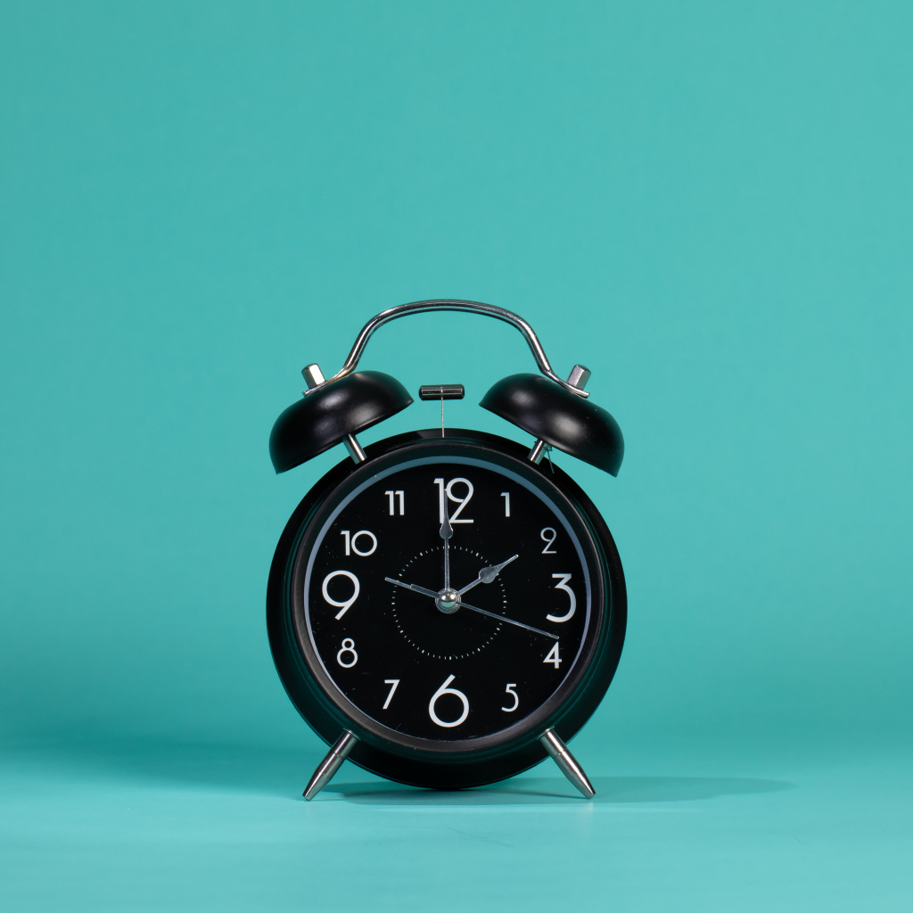Черный будильник на голубом фоне