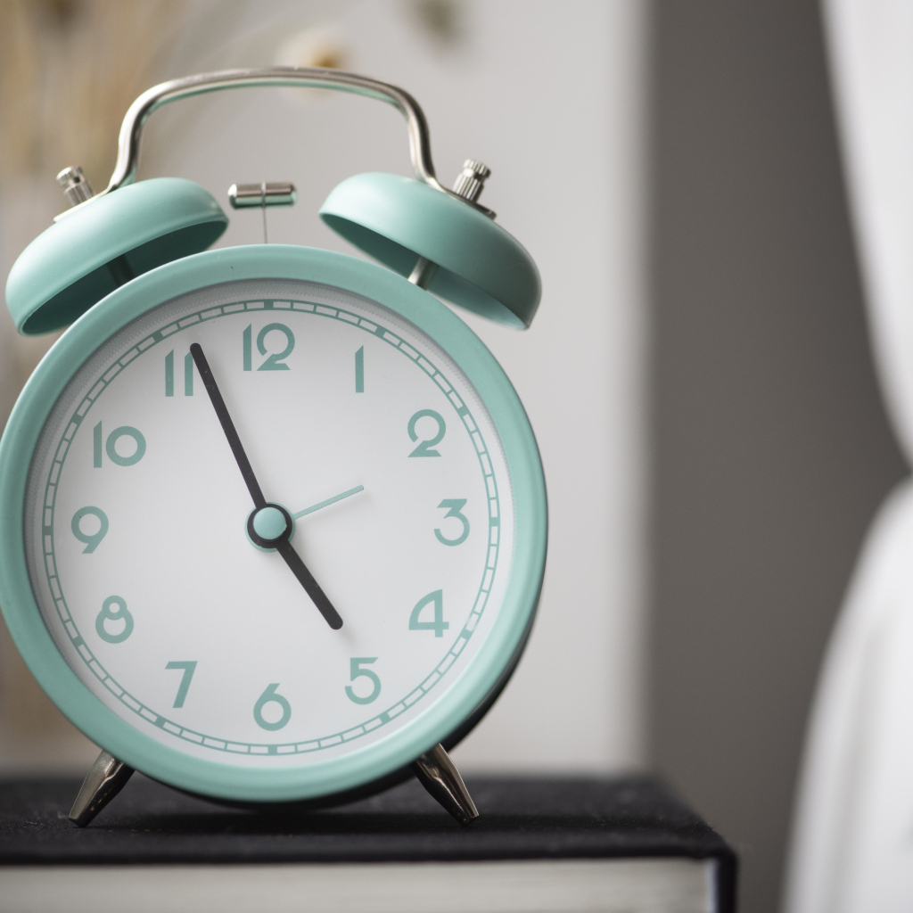 Голубой будильник стоит на книге в комнате