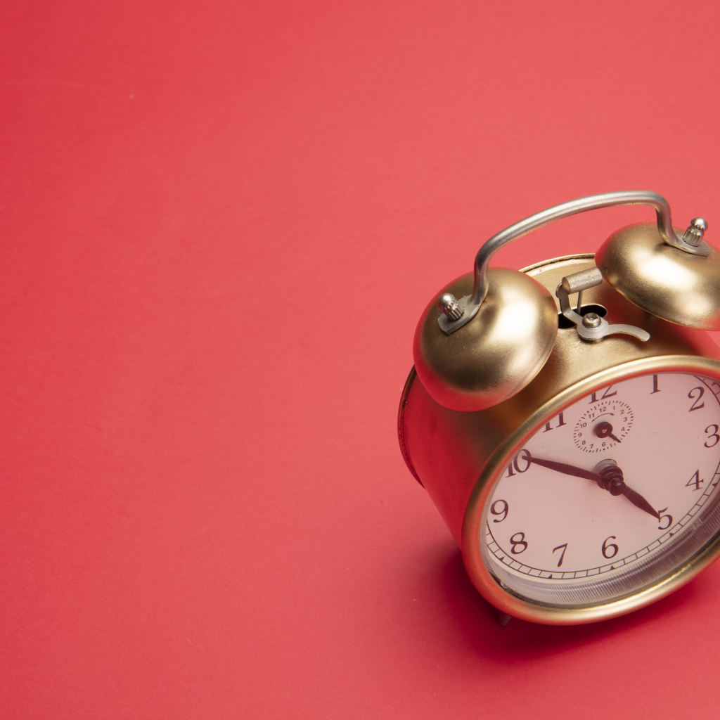 Золотой будильник на красном фоне