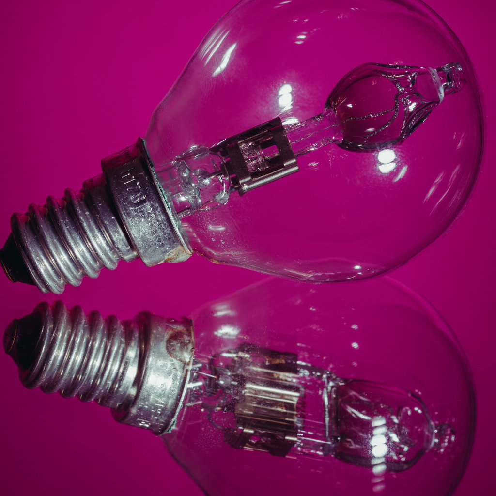 Лампочка отражается в поверхности на сиреневом фоне