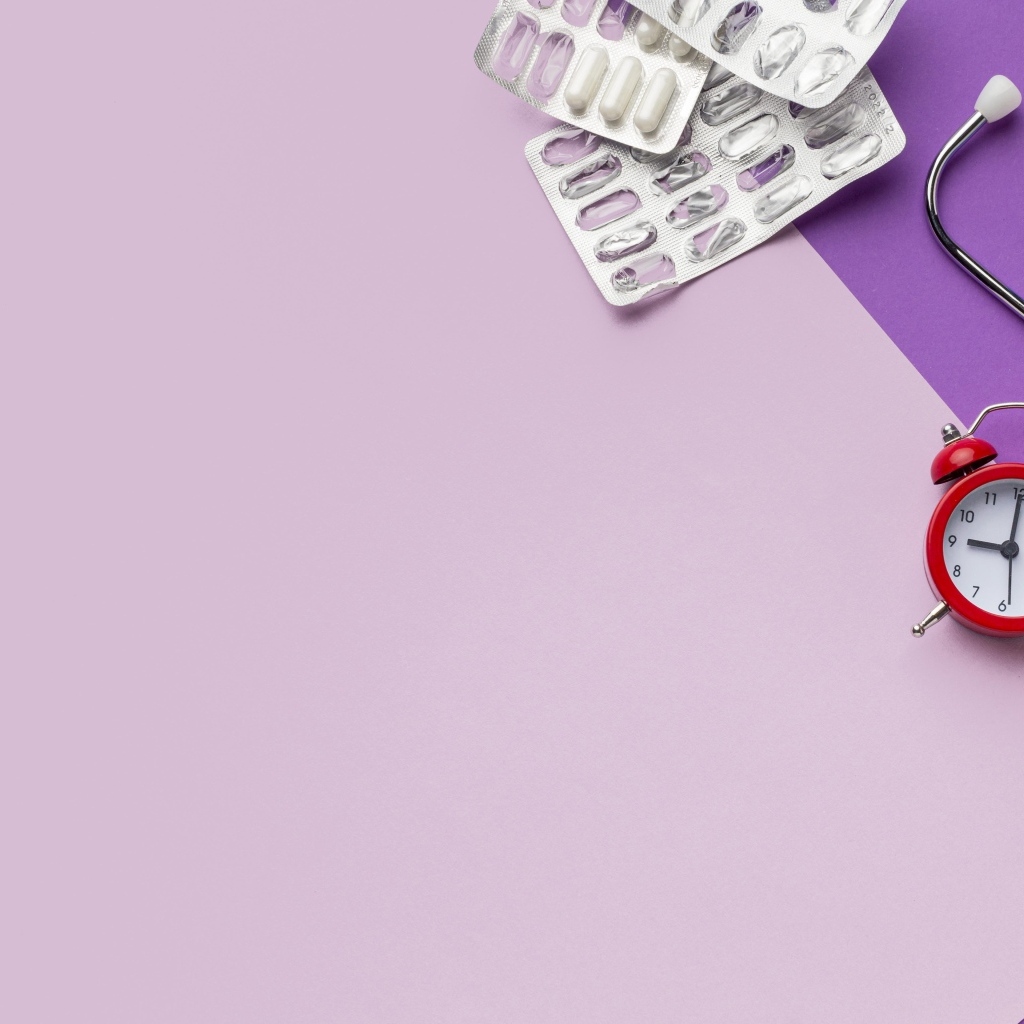 Таблетки, стетоскоп и будильник на сиреневом фоне