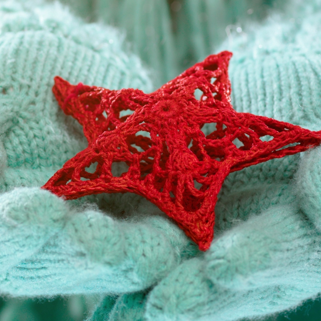 Красная вязаная звезда в руках в варежках