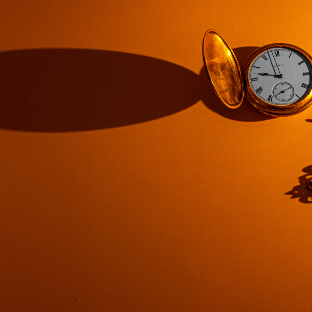 Тень от карманных часов на оранжевом фоне