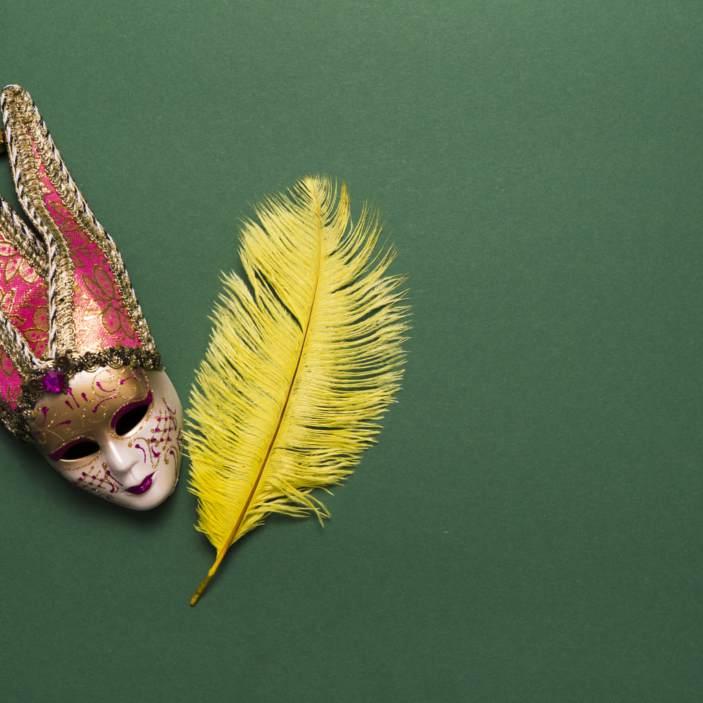 Венецианская маска и желтое перо на зеленом фоне
