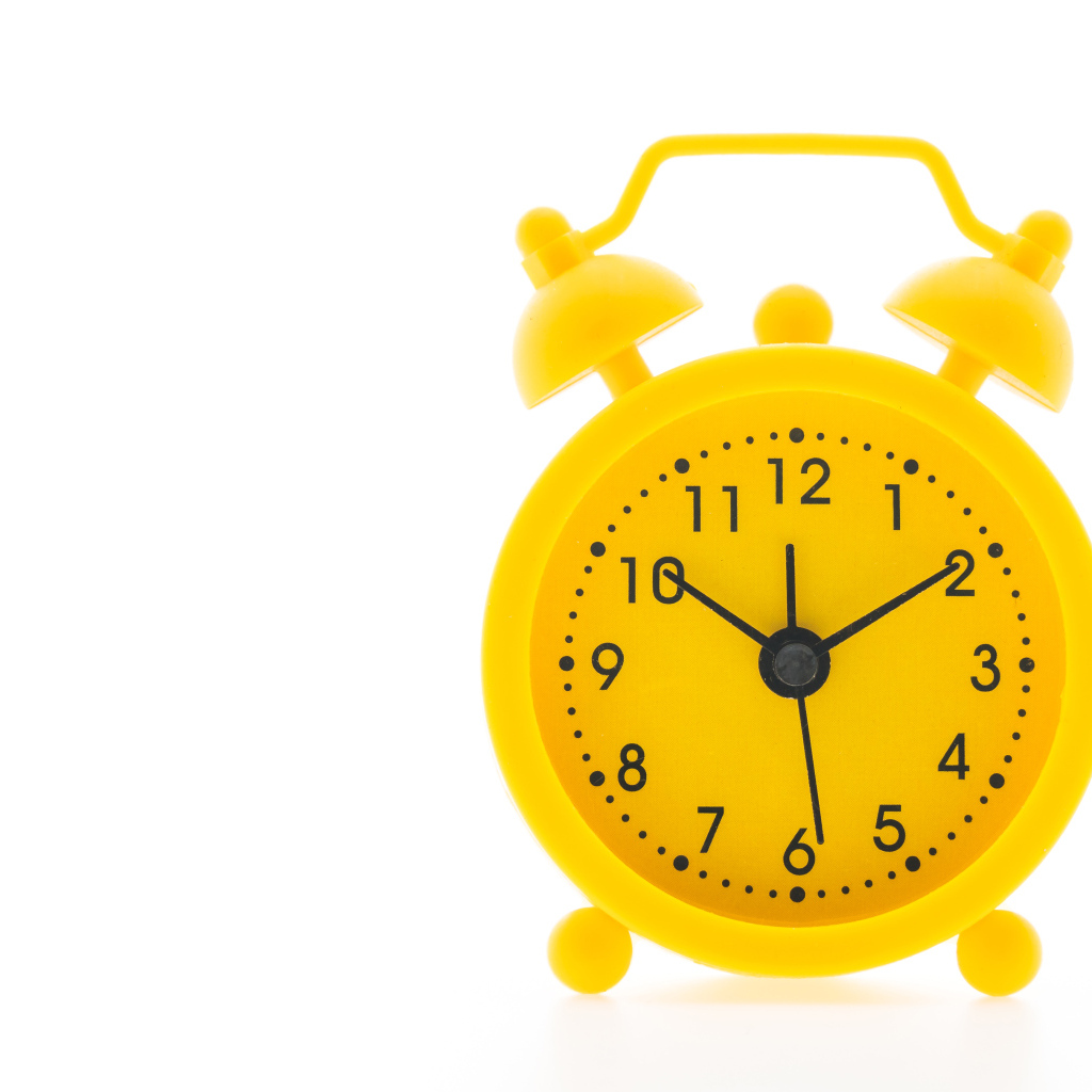 Желтый будильник на белом фоне