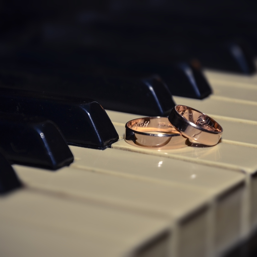 Два золотых обручальных кольца на клавишах пианино 