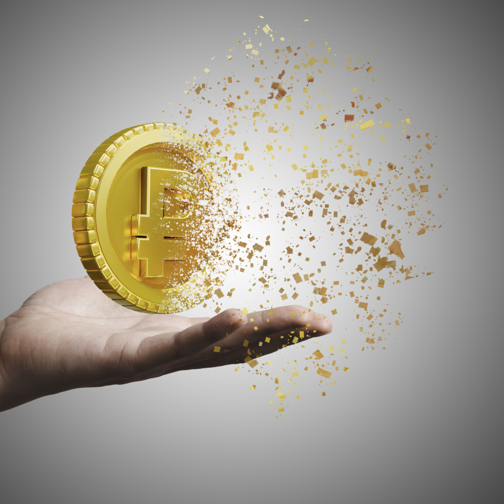 Монета разрушается на ладони на сером фоне