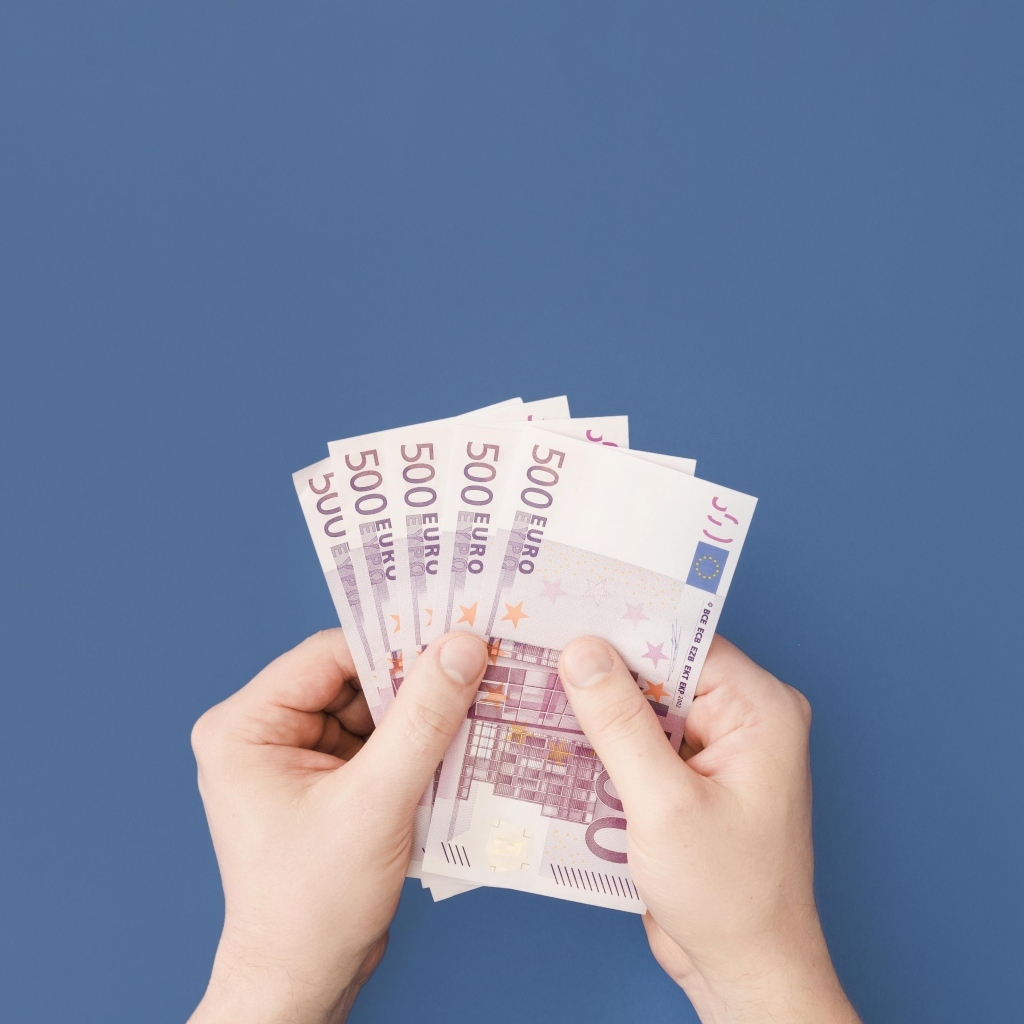 Купюры в пятьсот евро в руках на синем фоне