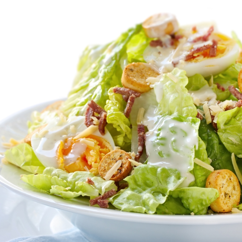 Салат Цезарь на большой белой тарелке