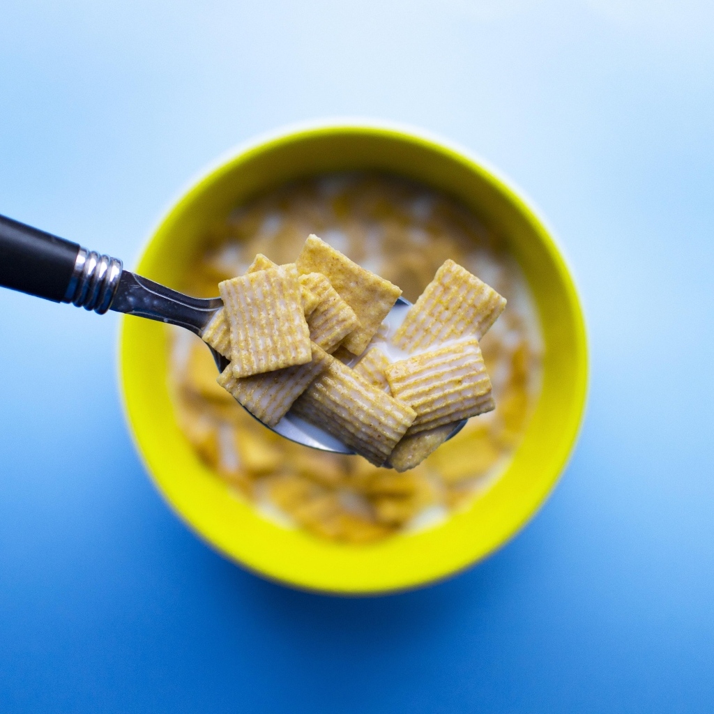 Хлопья с молоком на ложке на голубом фоне