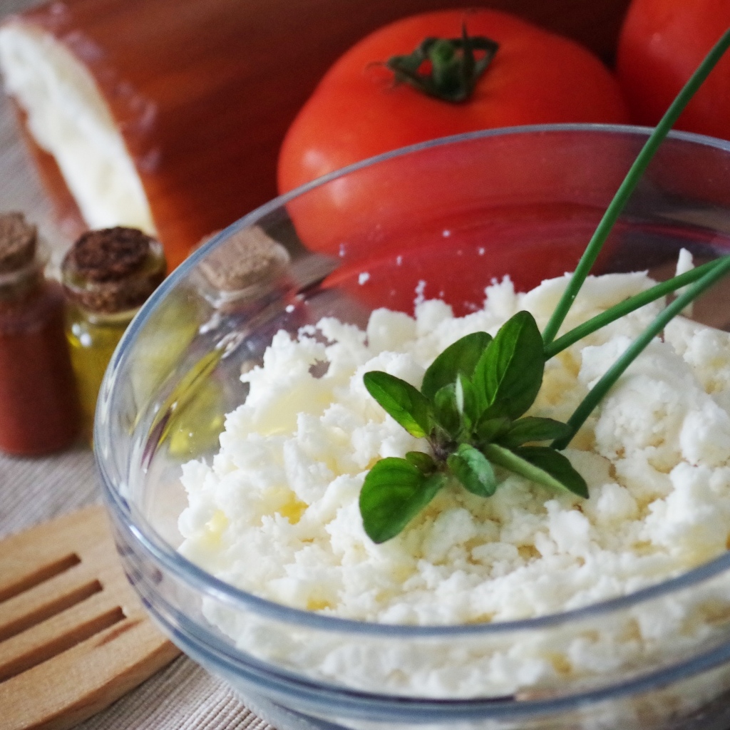 Творог в тарелке на столе с помидорами