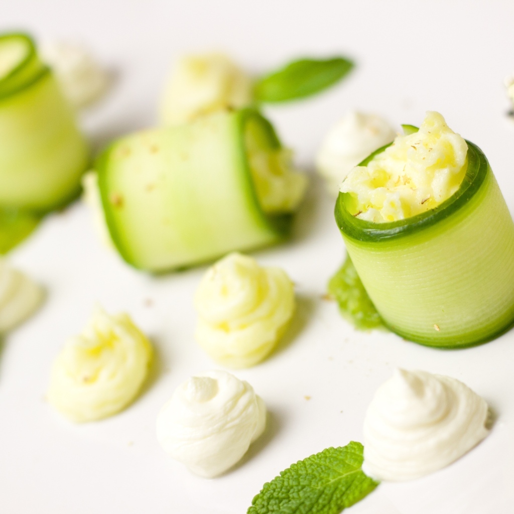 Рулетики из огурца с кремом на белом фоне