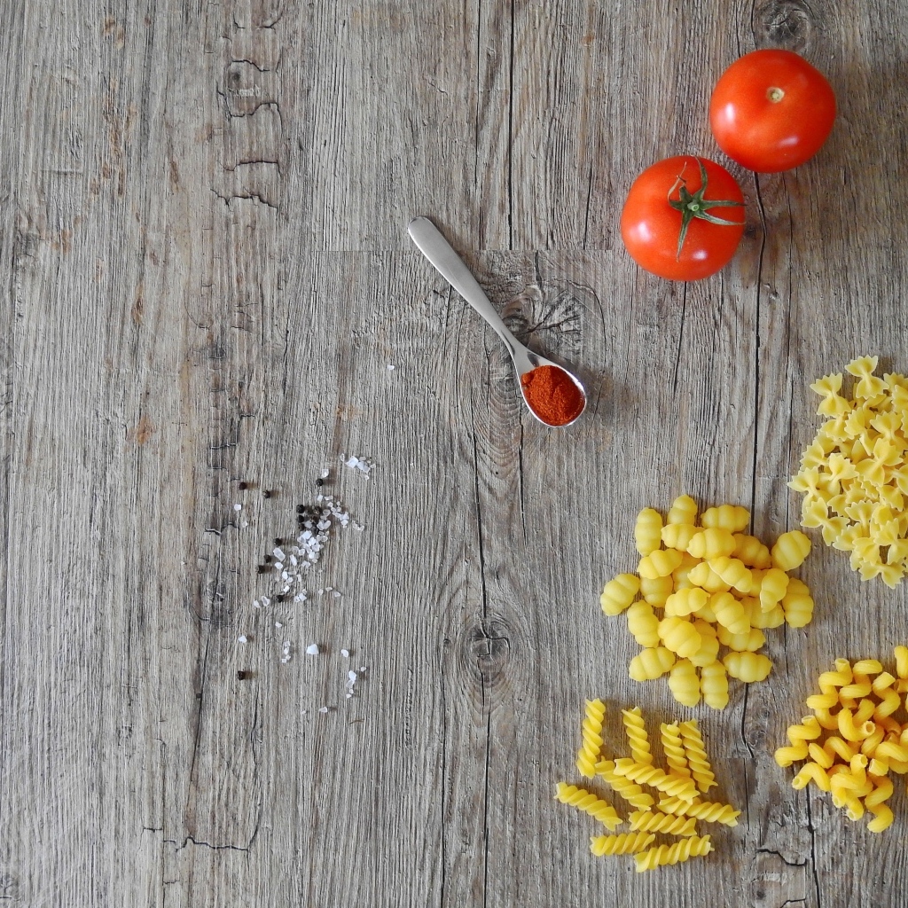 Разные виды макарон на столе с помидорами