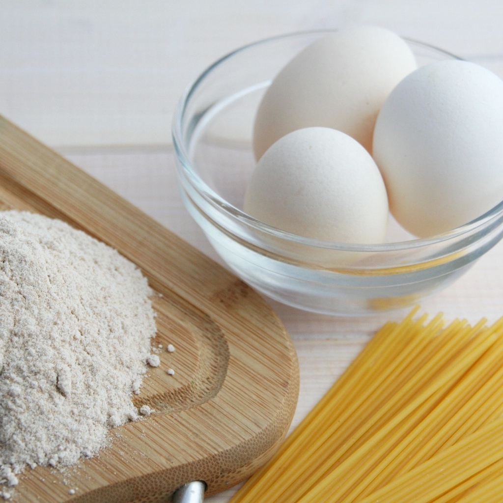 Яйца на столе с мукой и спагетти