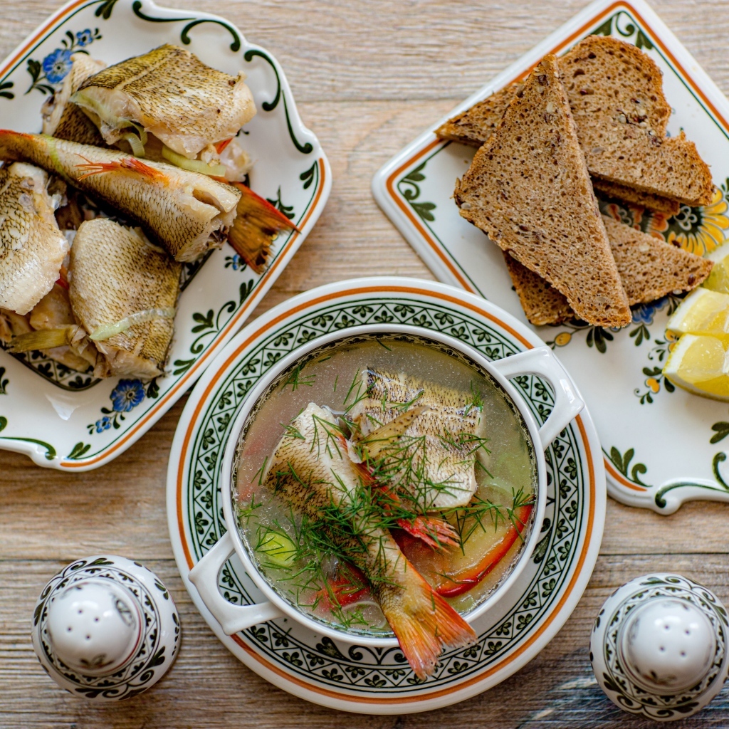 Уха на столе с хлебом и лимоном