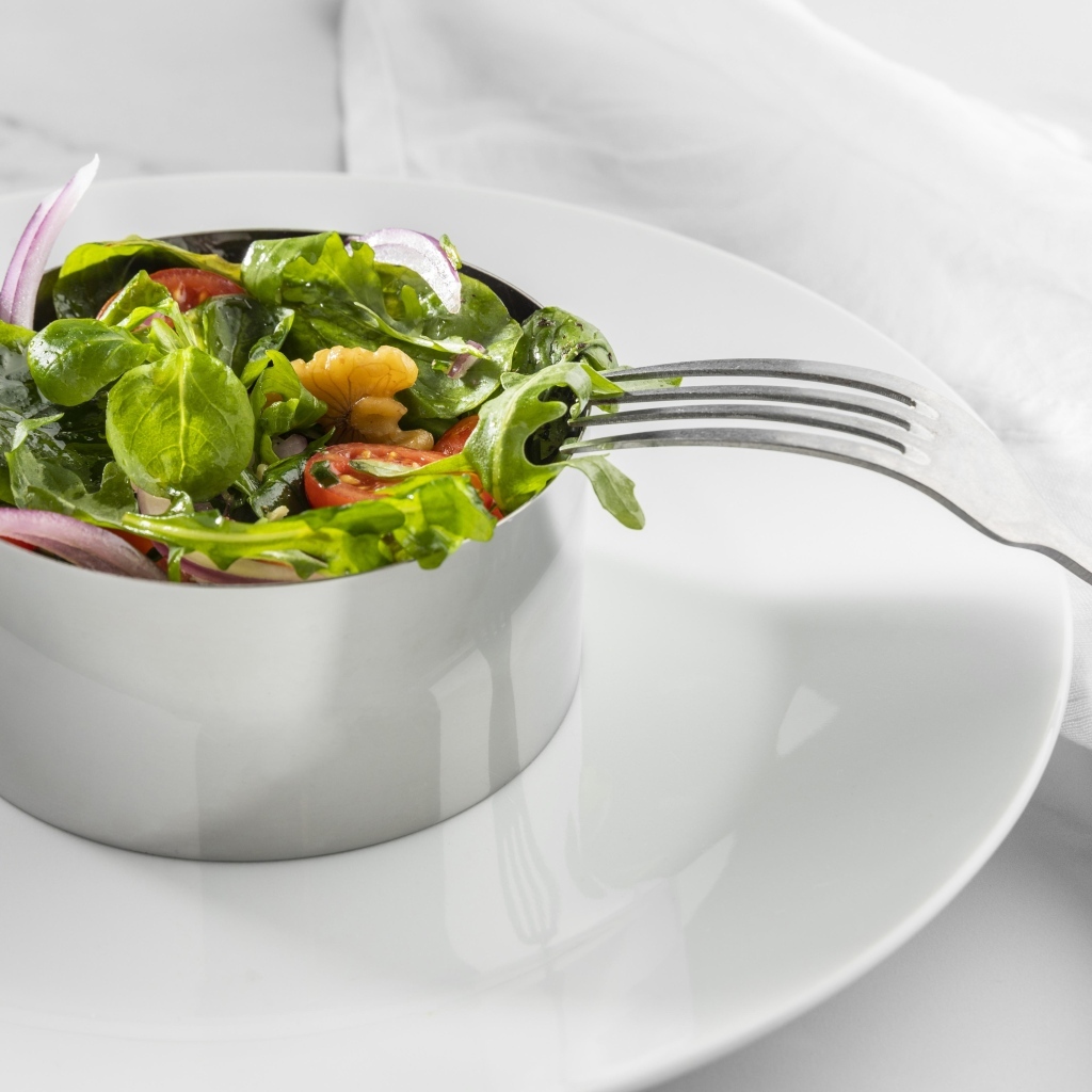 Зеленый салат с орехами на большой белой тарелке
