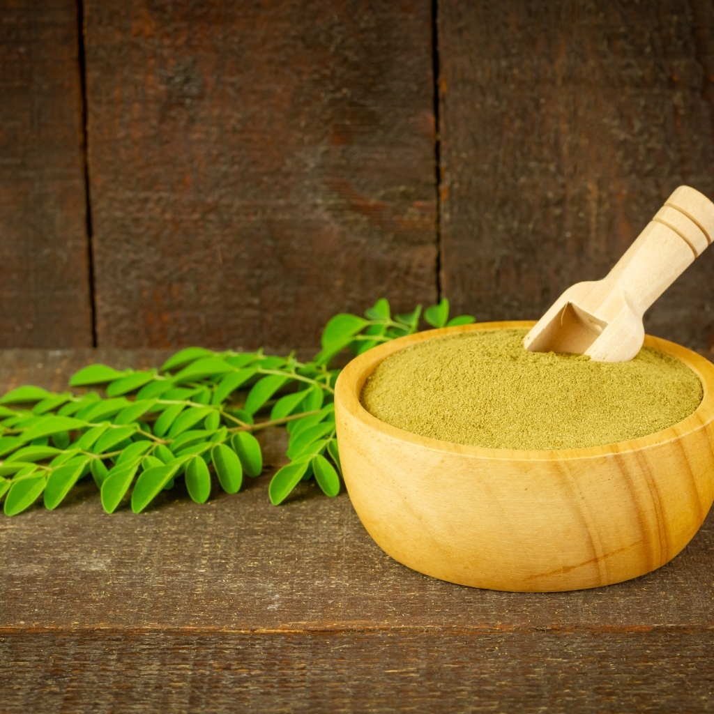 Порошок моринга на столе с листьями