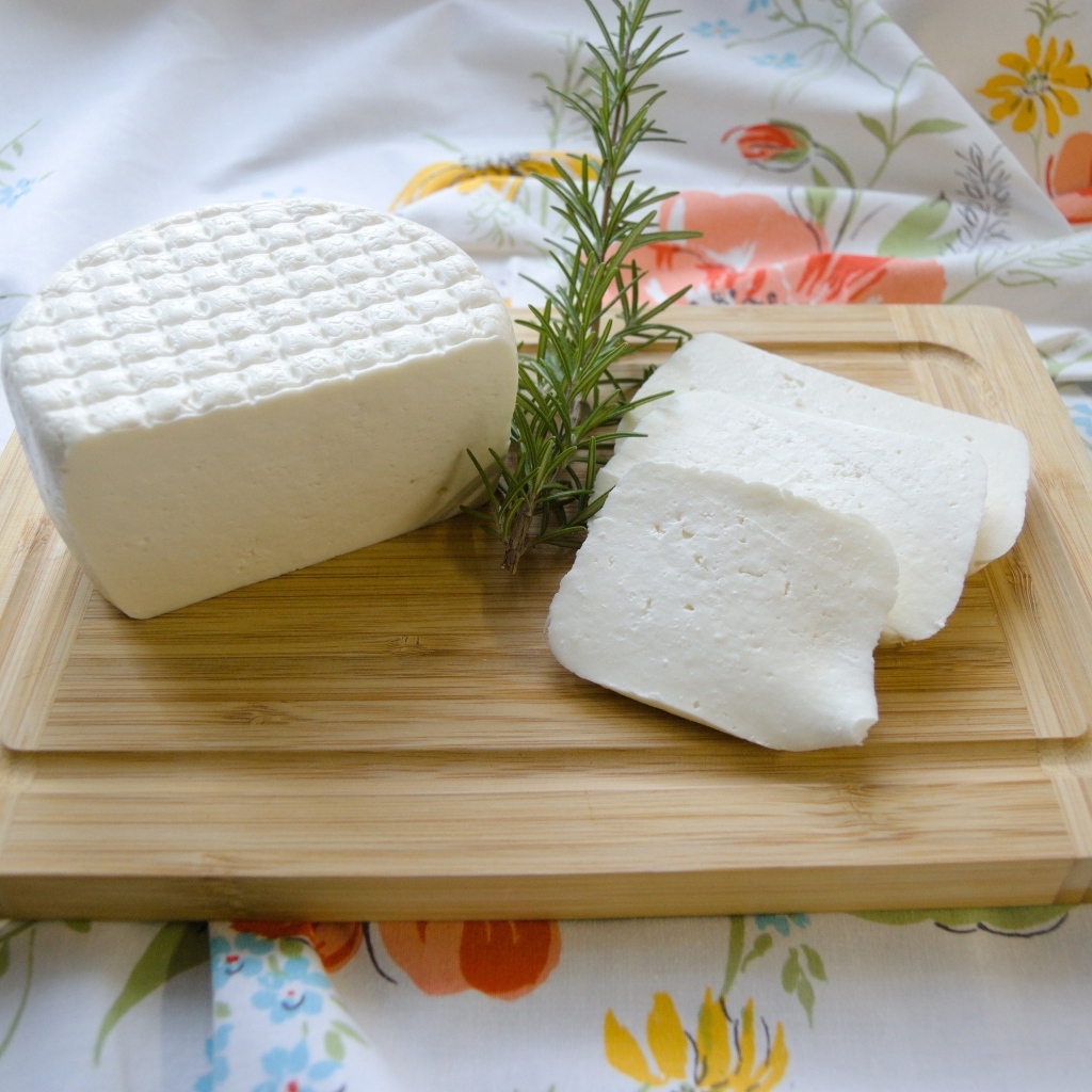 Кусок сыра с розмарином на разделочной доске