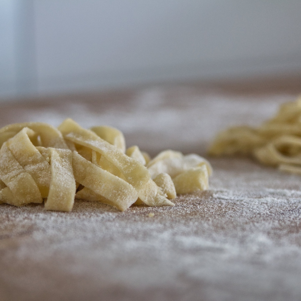 Сырое тесто для лапши на покрытом мукой столе