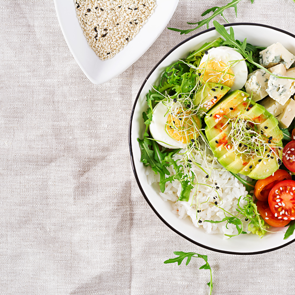 Рис с овощами и авокадо в тарелке