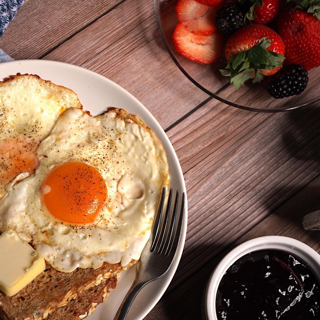 Яичница с гренками на столе с клубникой