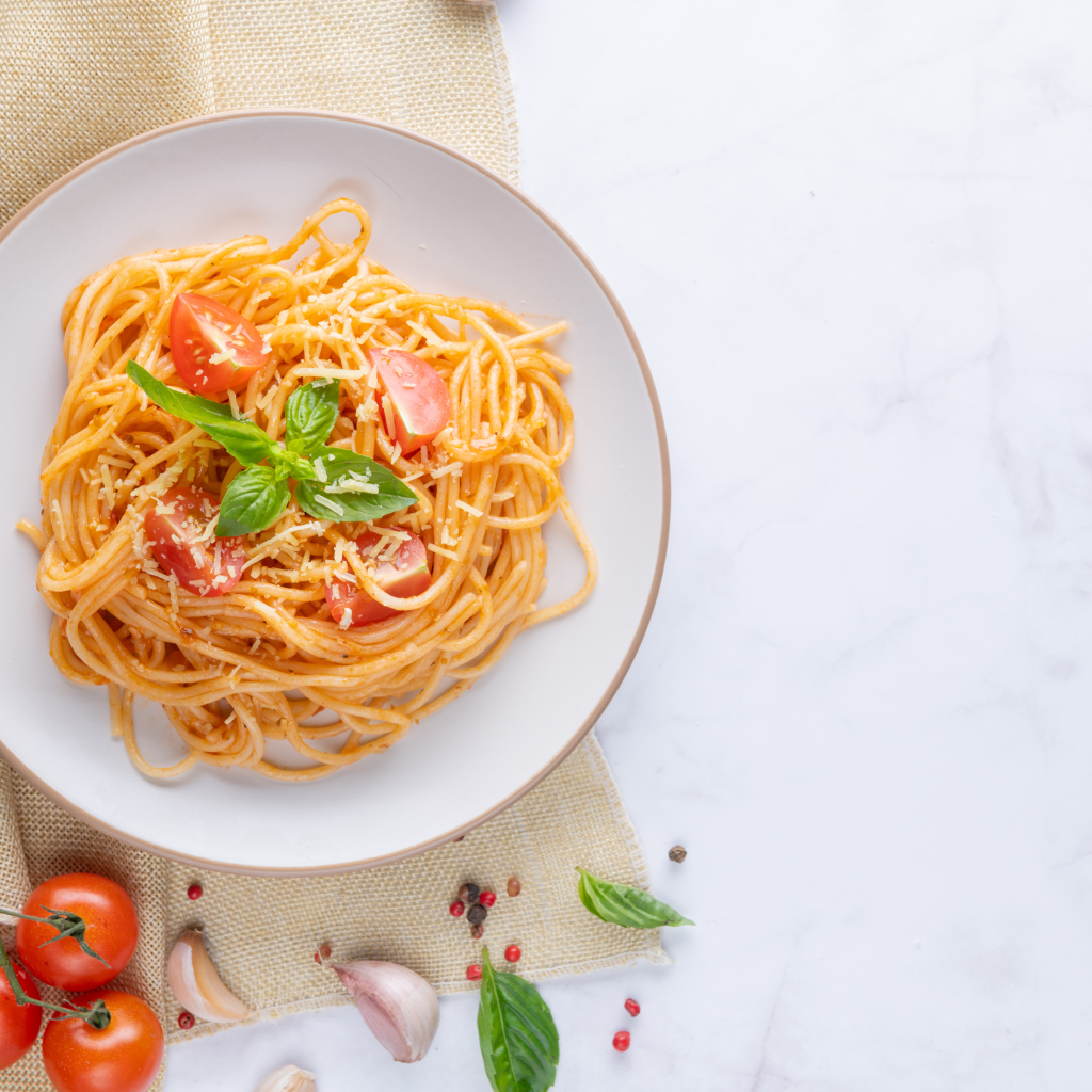Спагетти с помидорами в тарелке на столе