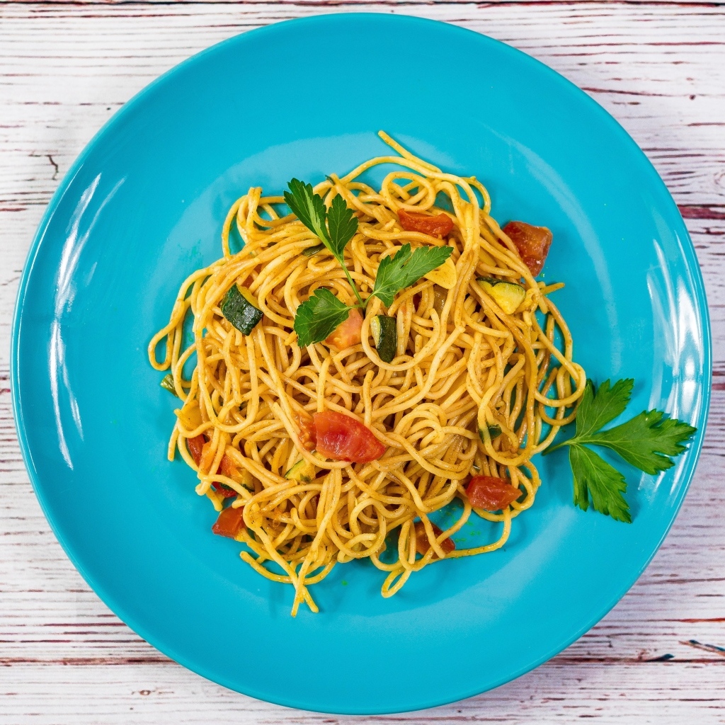 Спагетти с овощами  на голубой тарелке